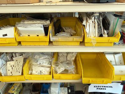 Outlet covers in yellow bins on a warehouse shelf.